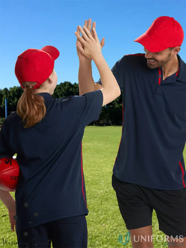 Two people in navy blue polo shirts and red caps high-fiving on grass, 10x Bundle Cap