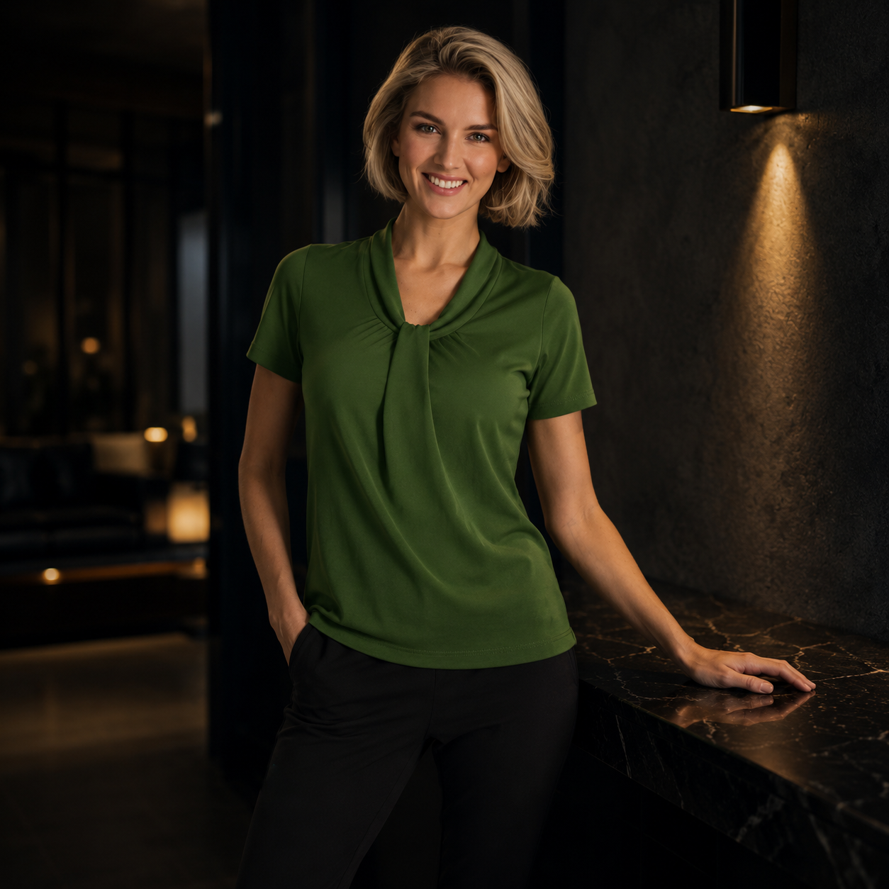 Woman wearing a green blouse standing in a dimly lit room.