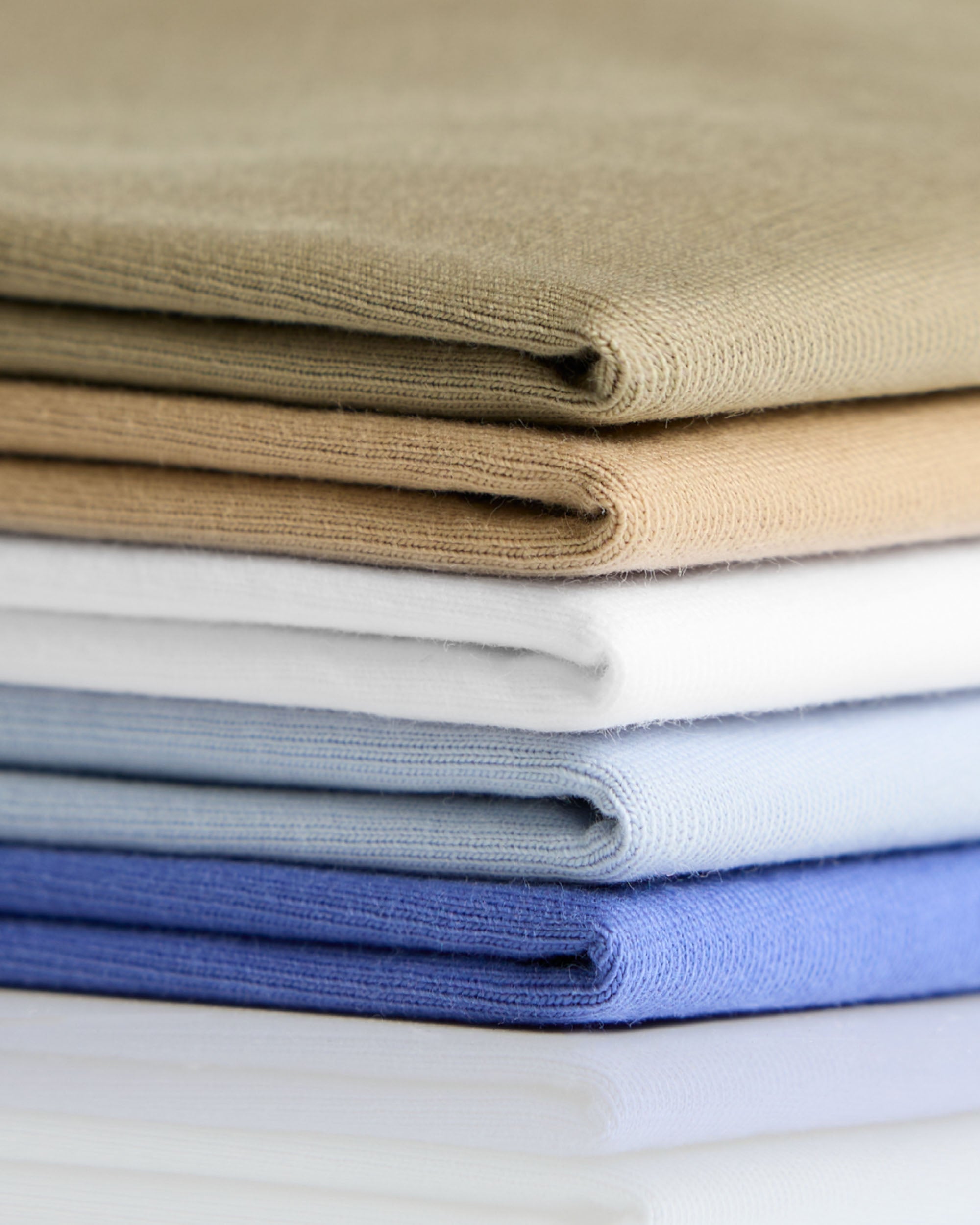 Stack of neatly folded classic heavyweight cotton t-shirts in earthy tones and blues perfect for workwear uniforms