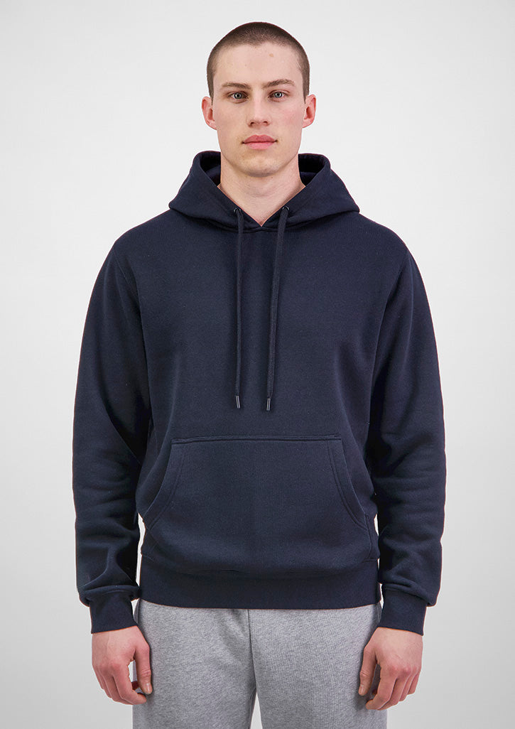 Man wearing a navy blue hoodie and gray pants on a white background