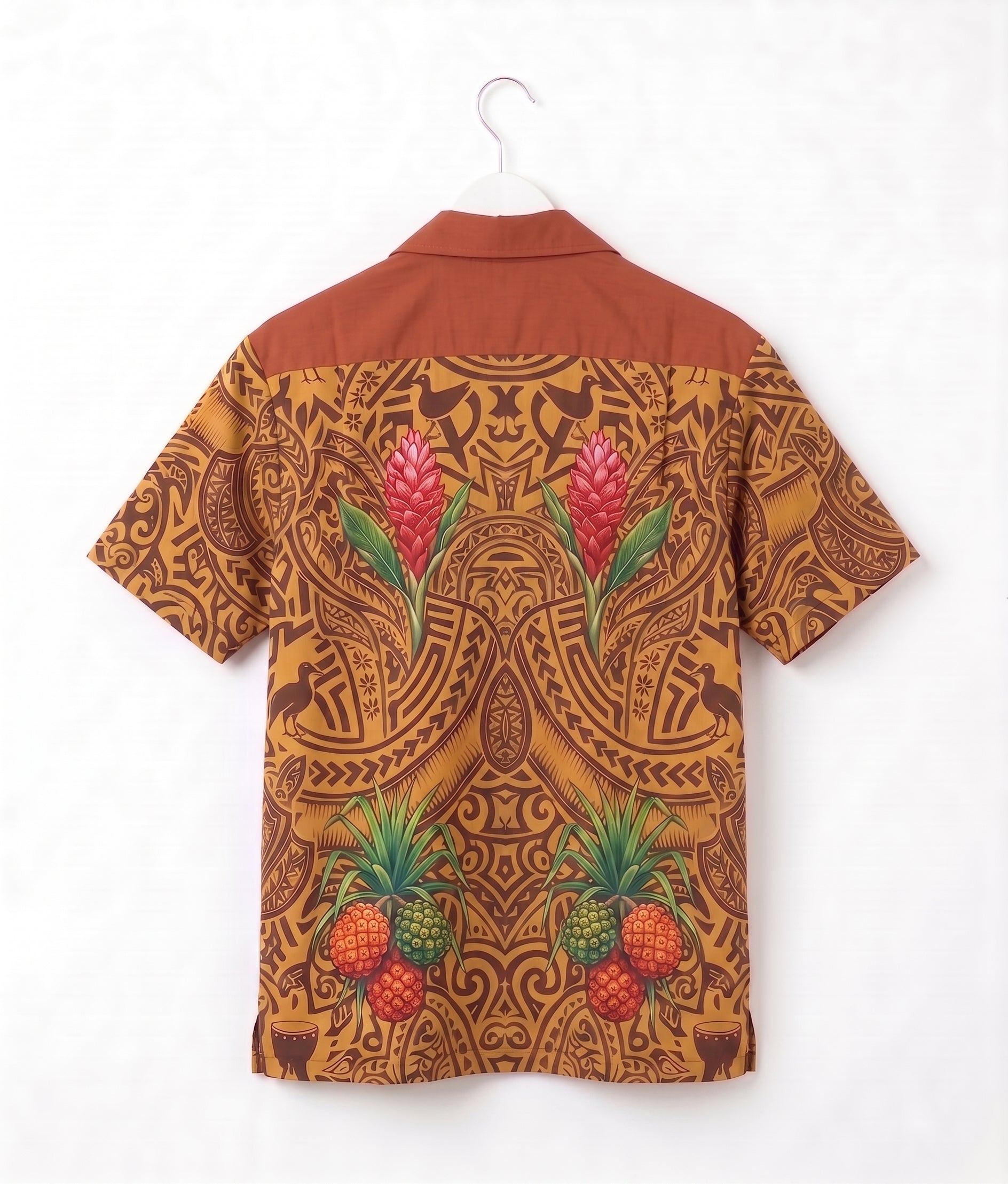 A short-sleeve camp collar shirt shown from the back, hanging on a white hanger against a white wall. The shirt features a warm rust-brown yoke and a back print in a golden-brown tribal pattern decorated with pink tropical flowers and green pineapples.