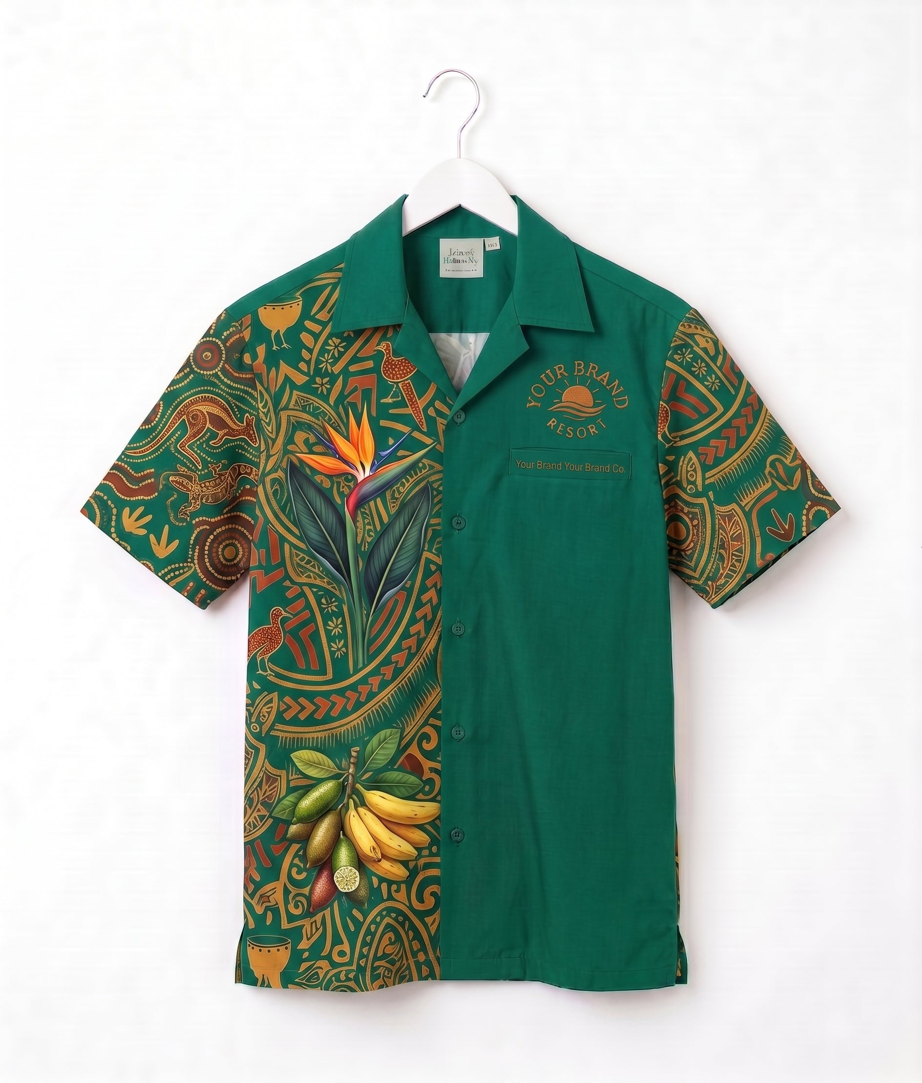 A green short-sleeve button-up shirt with a tropical and Polynesian-inspired print on the sleeves and left side, hanging on a white hanger against a white background. The right side is solid green with 'YOUR BRAND WEAR' printed on the chest.