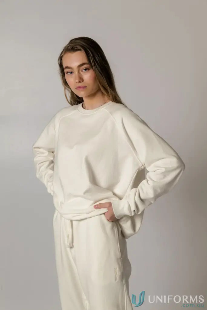 Woman wearing a matching cream Archie Crew Sweat sweatshirt and sweatpants for a comfy look