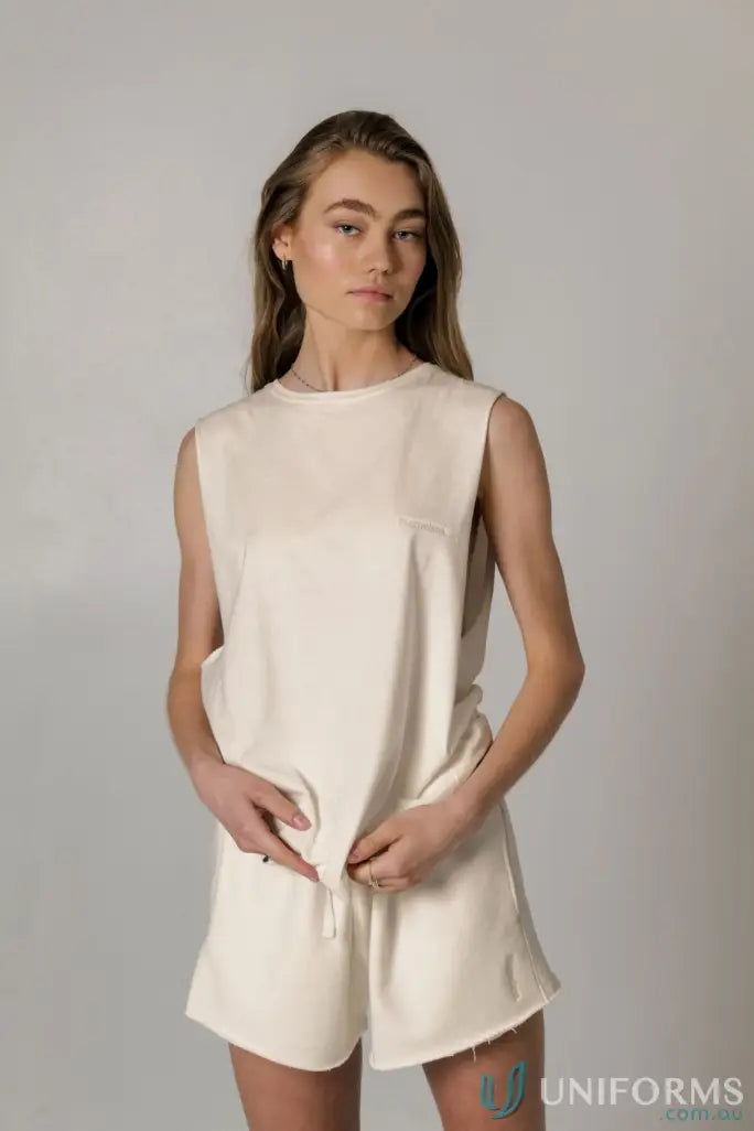 Woman in cream Cotton Tank Top with raw cut sleeve and nameless chest embroidery
