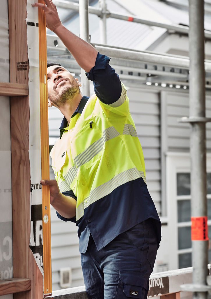 Man in HiVis segmented tape workwear shirt Zw470 holding level on wall