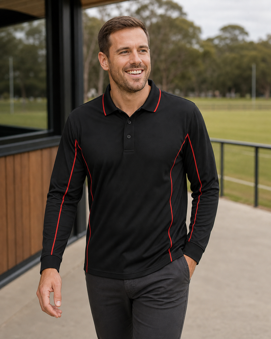Australian male model wearing black Podium Piping long sleeve polo with red trim