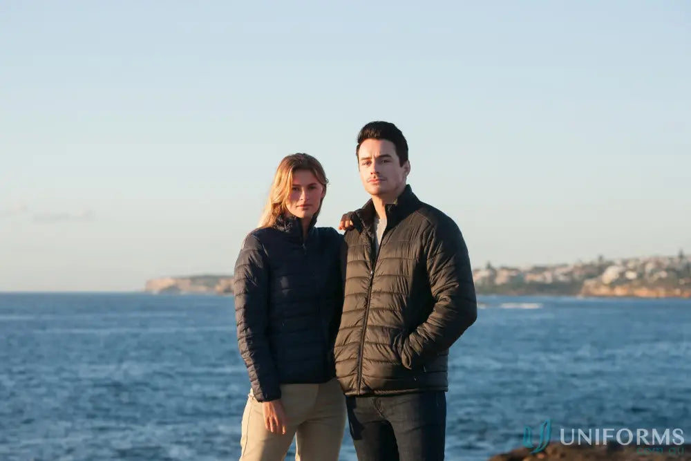 Two people in puffer jackets by the ocean, perfect for workwear or casual uniforms