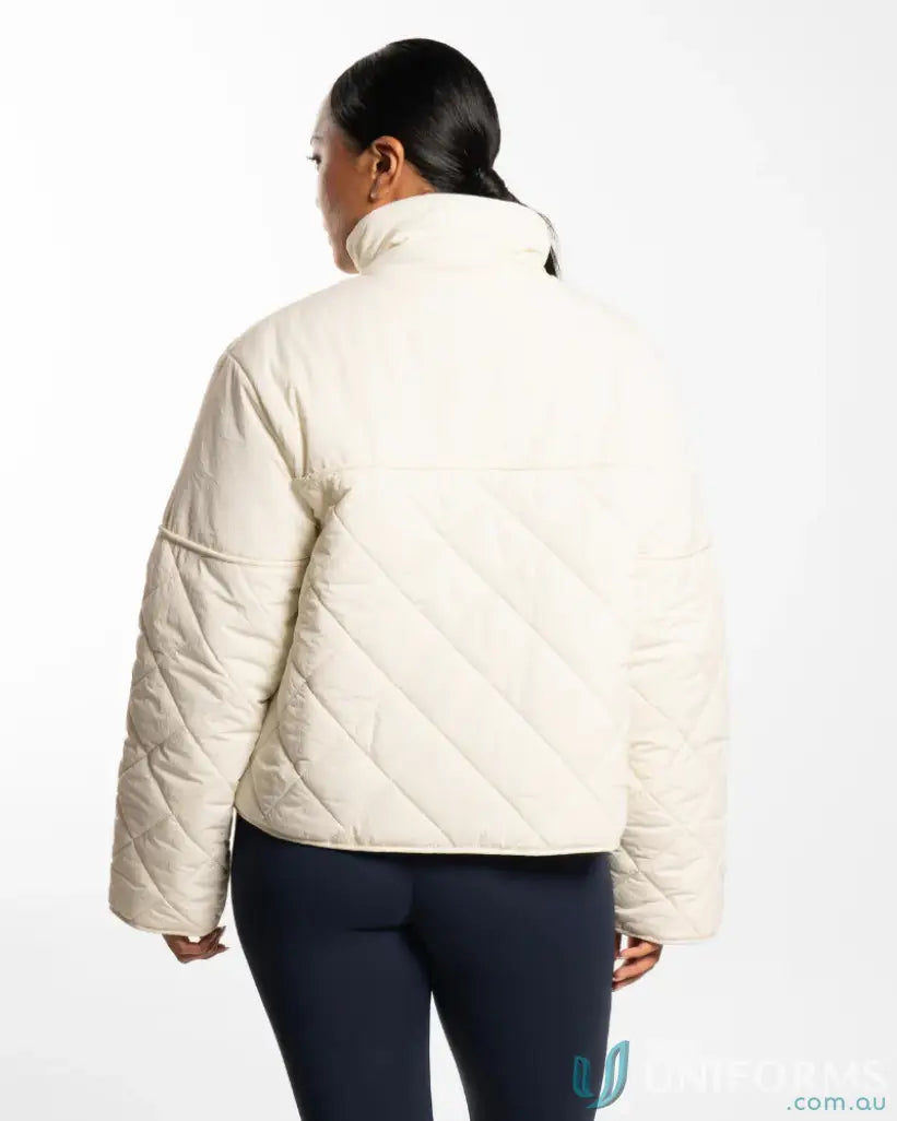 Cream quilted puffer jacket with high collar and drawstring hem, likely made of synthetic material.