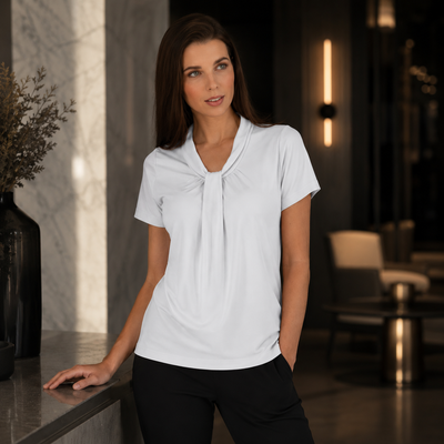 Woman wearing a white blouse with a knot detail in a modern indoor setting
