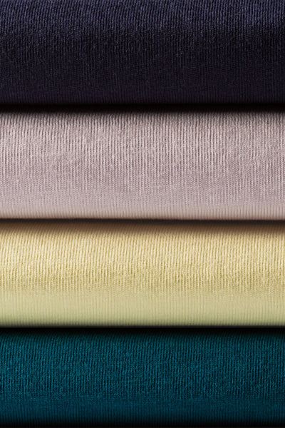 Stack of four neatly folded classic heavyweight ribbed knit t-shirts in navy mauve pale yellow and teal for workwear uniforms