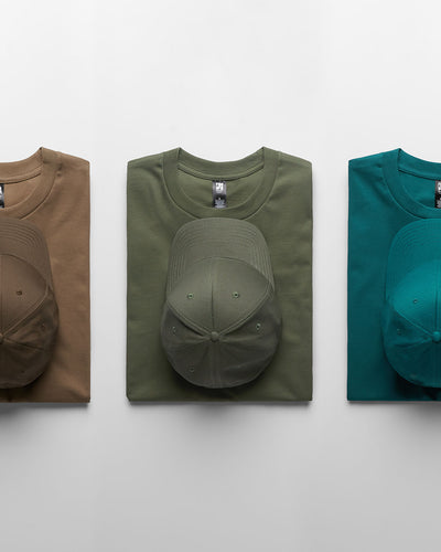 Three classic heavyweight t-shirts in tan olive green and teal paired with matching caps for durable work uniforms