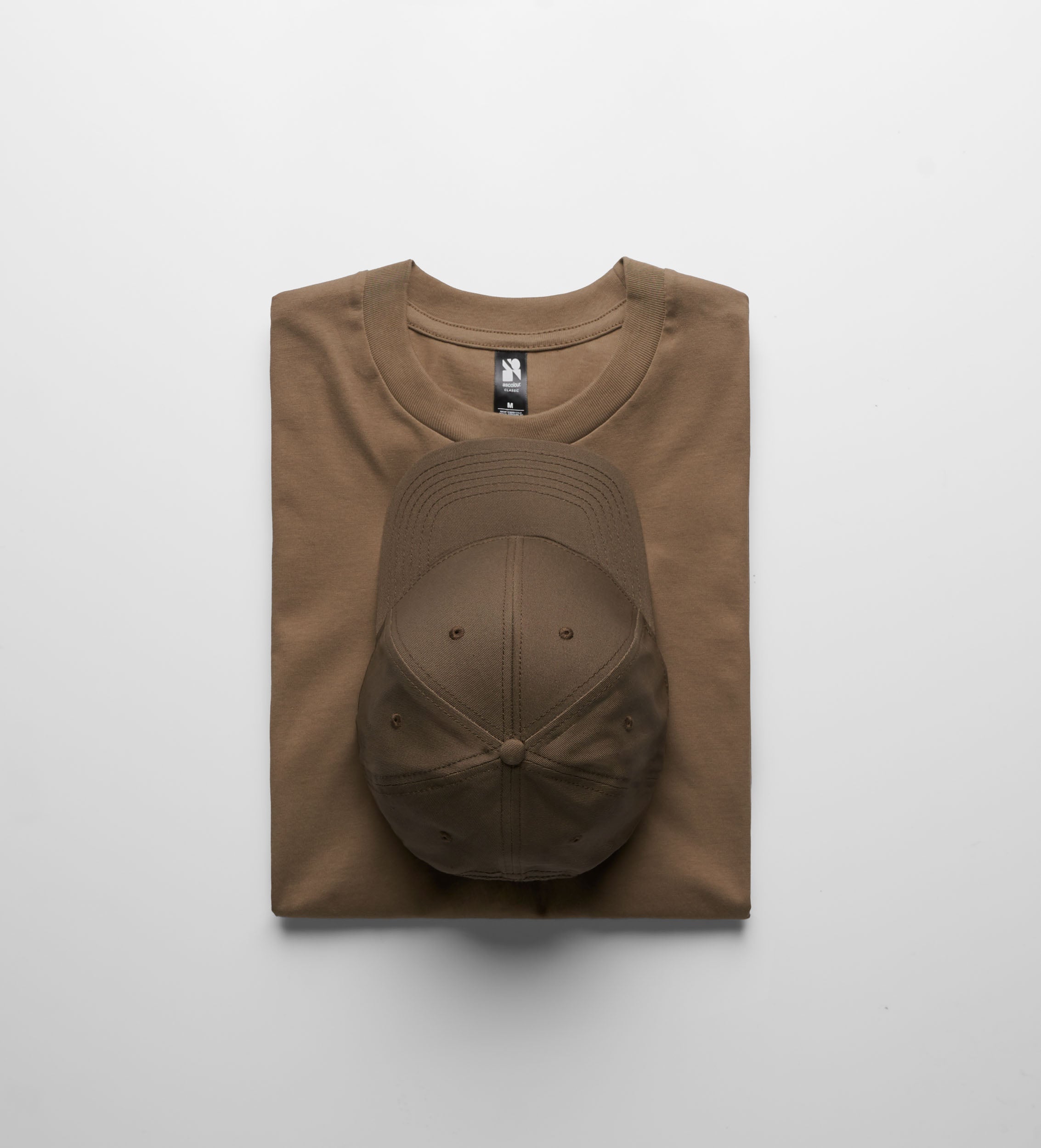 A tan cotton classic heavyweight t-shirt neatly folded with a brown baseball cap perfect for workwear uniforms