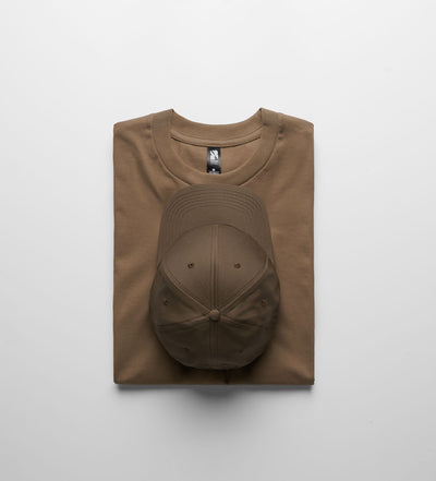 A tan cotton classic heavyweight t-shirt neatly folded with a brown baseball cap perfect for workwear uniforms