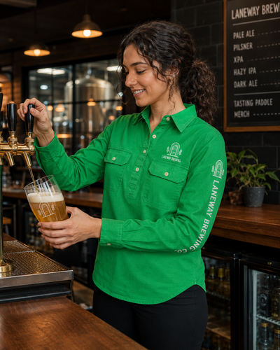 A woman in a bright green long-sleeve button-up shirt with 'LANWAY BREWING CO.' printed on the chest and sleeve, pouring beer from a tap into a glass at a bar.
