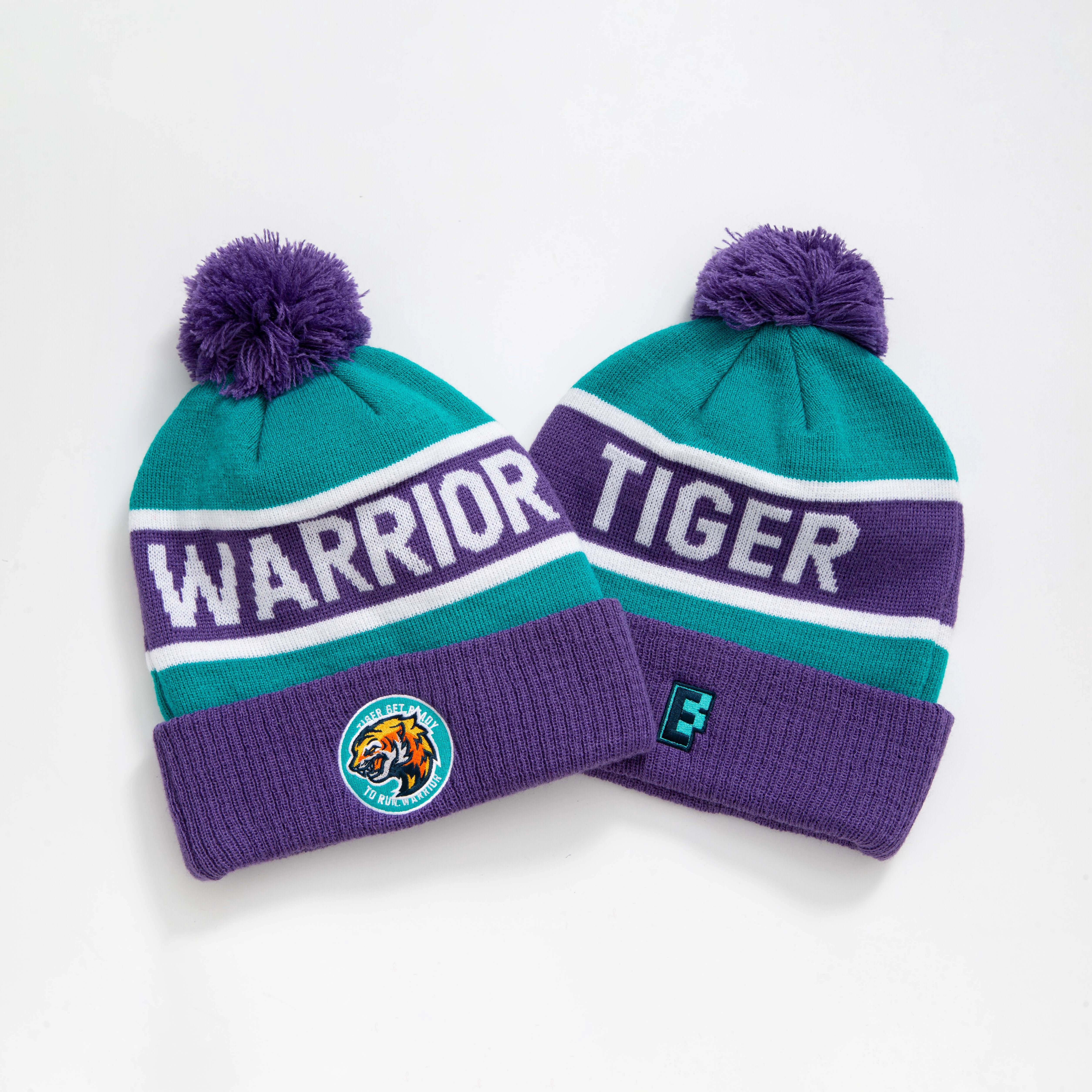 Teal and purple knitted pompom beanie with white warrior and tiger lettering and team logos perfect for work uniforms