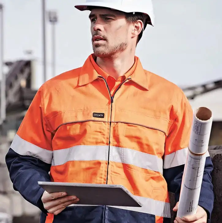 Man wearing high visibility orange work jacket in Australia holding tablet and construction plans on outdoor worksite