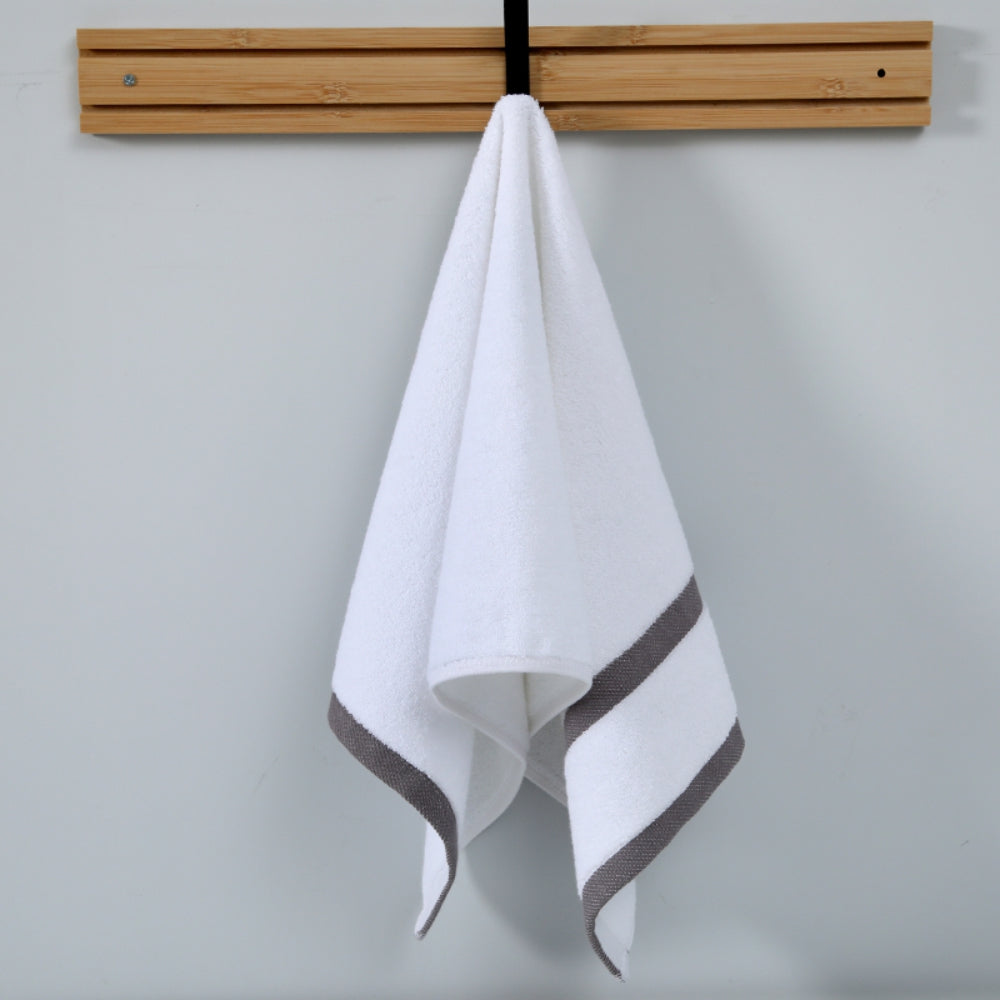 White towel with gray border hanging on a wooden rack against a light gray background