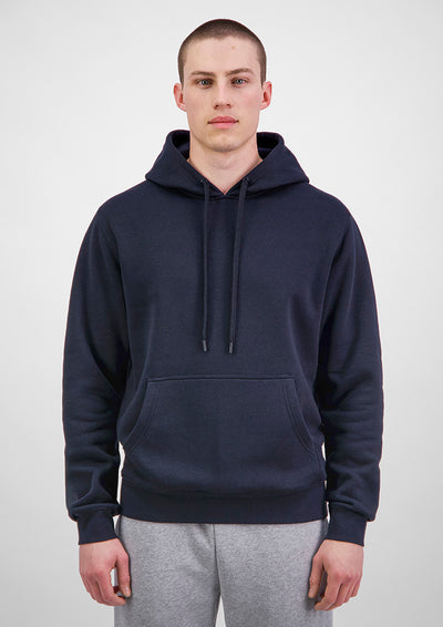 Man wearing a navy blue hoodie and gray pants on a white background