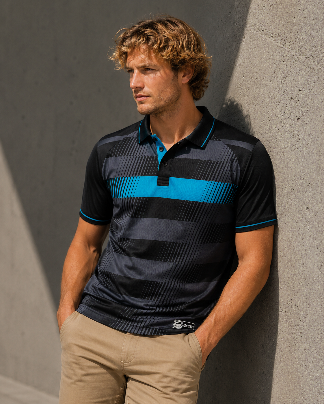 Man wearing a black and blue striped polo shirt against a gray wall