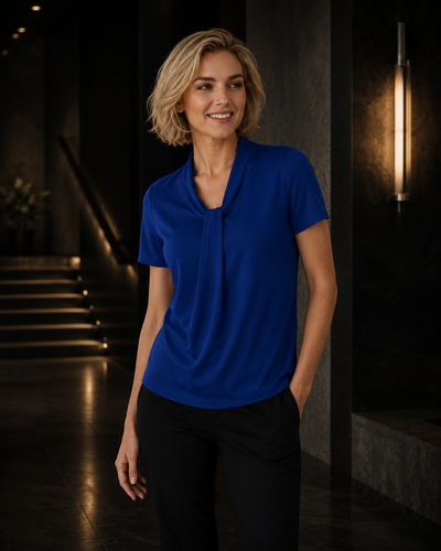 Woman wearing a blue shirt standing in a dimly lit room.