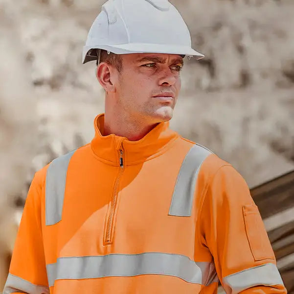Person wearing orange high visibility jacket and white hard hat in Australia on outdoor construction worksite