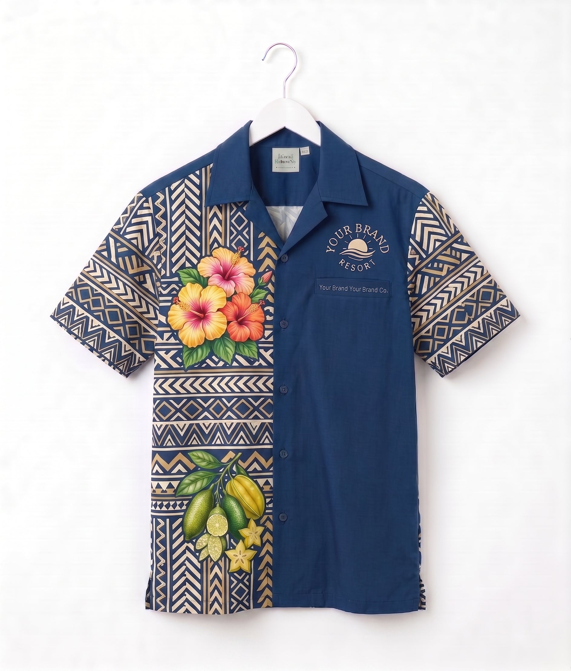 A short-sleeve button-up camp shirt hanging on a white hanger against a white wall. The shirt features a navy blue body with geometric patterned sleeves and lower front panel, decorated with tropical floral and fruit prints including hibiscus flowers and bananas.