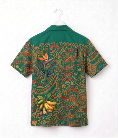 A short-sleeve camp collar shirt with a green yoke and a highly detailed, colorful tribal-style print on the body, featuring a bird of paradise flower, bananas, and abstract motifs. The shirt is shown hanging on a white plastic hanger against a white background.