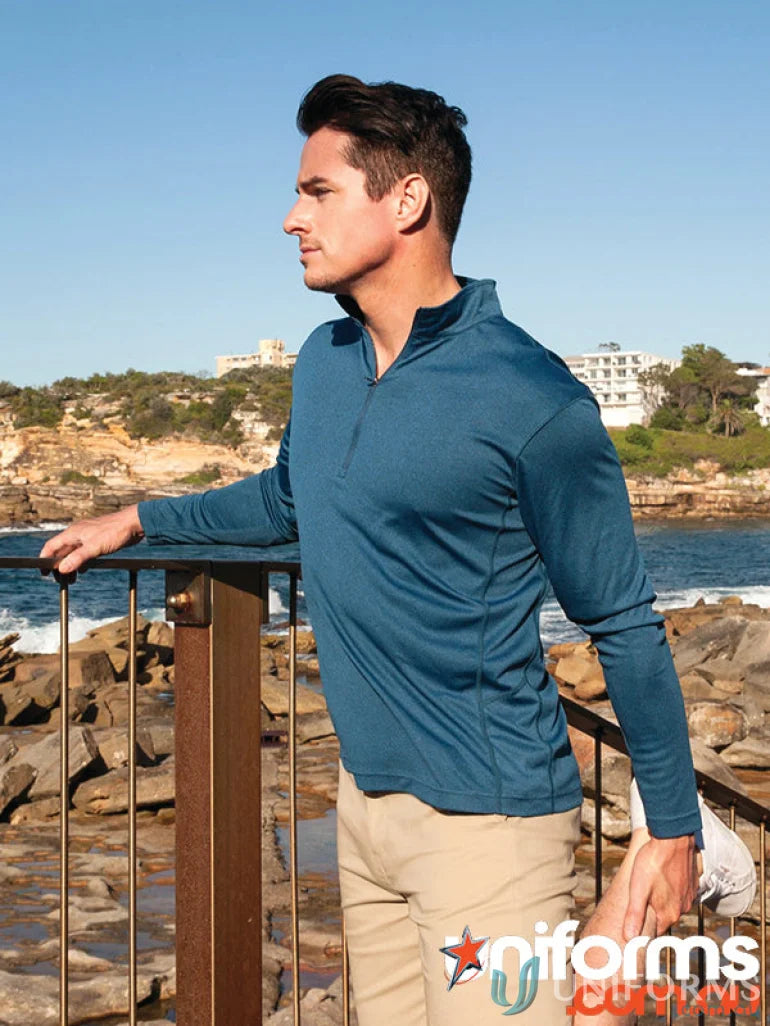 Man stretching in Apex Baselayer active dry uniforms, blue long-sleeve shirt, khaki pants