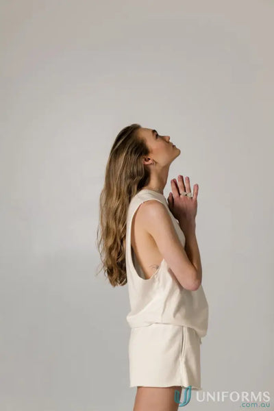 Woman in cream-colored Cotton Tank Top with raw cut sleeve and nameless chest embroidery