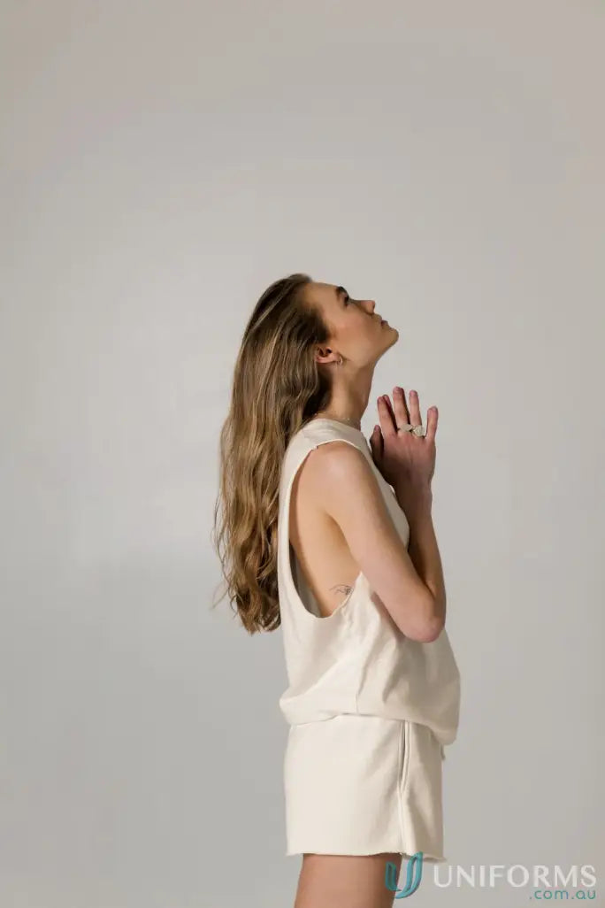 Woman in cream-colored Cotton Tank Top with raw cut sleeve and nameless chest embroidery