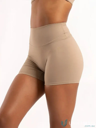 Beige high-waisted invicible scrunch latte shorts with smooth form-fitting fabric ideal for comfortable workwear and uniforms