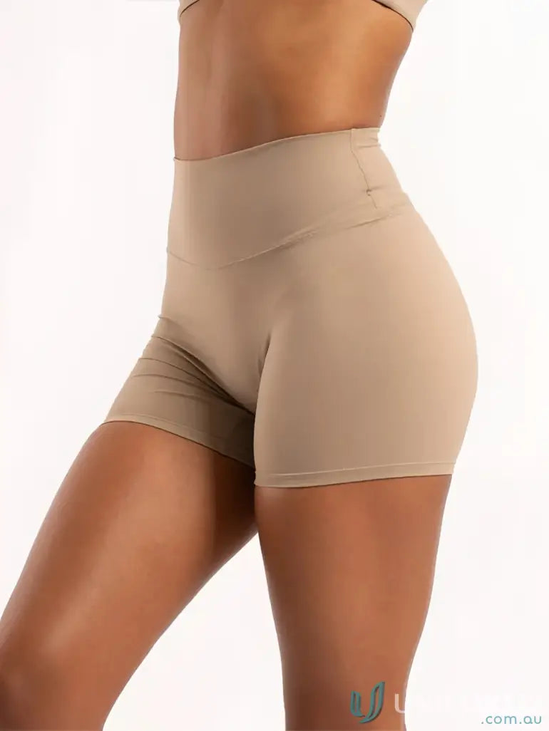 Beige high-waisted invicible scrunch latte shorts with smooth form-fitting fabric ideal for comfortable workwear and uniforms
