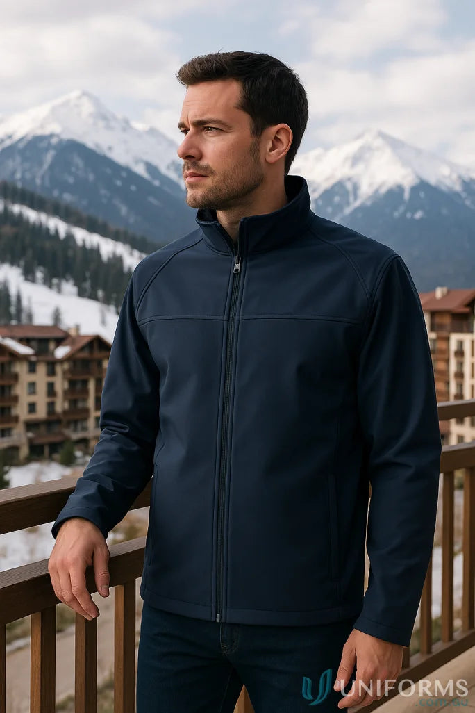 Man in JBs Layer Softshell Jacket on balcony with snowy mountains in background