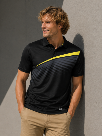 Man wearing a black polo shirt with a yellow stripe against a gray wall