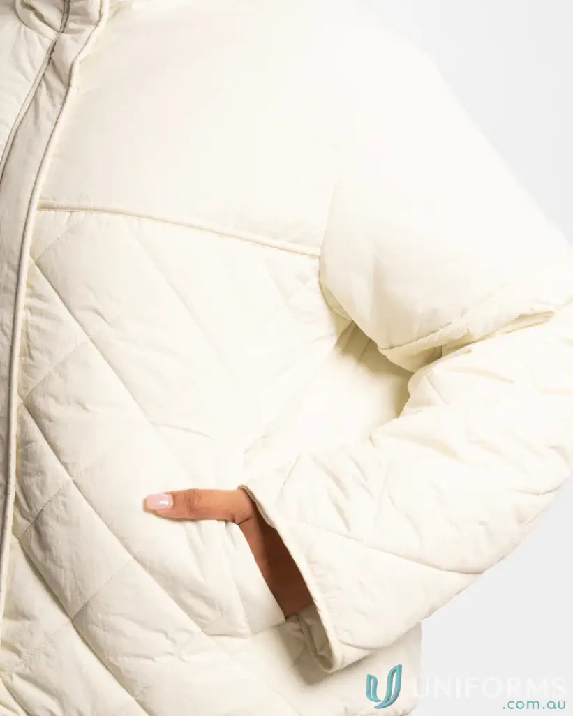 Cream puffer jacket with quilted design and zipper closure.