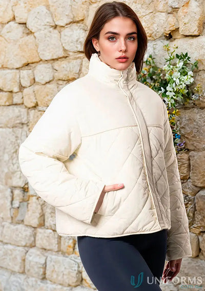 Cream quilted puffer jacket with high collar and long sleeves.