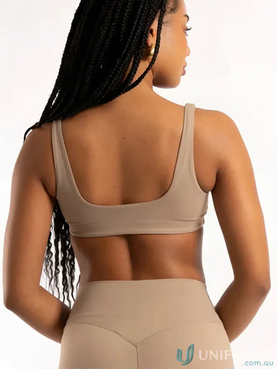 Beige seamless sports bra with thin straps and minimalist design perfect for workwear or uniforms layering