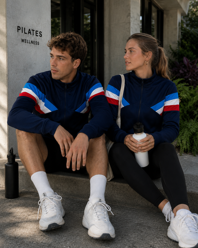 Two people sitting outdoors, wearing matching athletic outfits with red, white, and blue stripes.